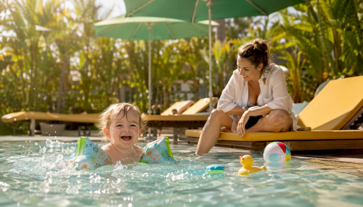 Ein Kind mit Schwimmflügeln tollt vergnügt im Pool herum.